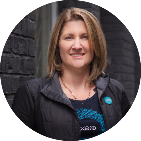 Woman wearing a Xero shirt standing in front of a brick wall